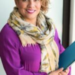 Woman Smiling and Holding Teal Book