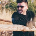 Man in Sunglasses Leaning on Fence Outdoors